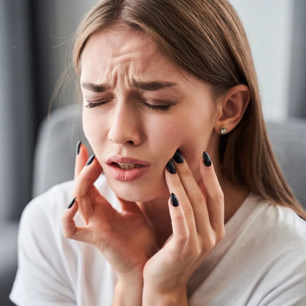 A Woman With Toothache Holding Her Face In Pain