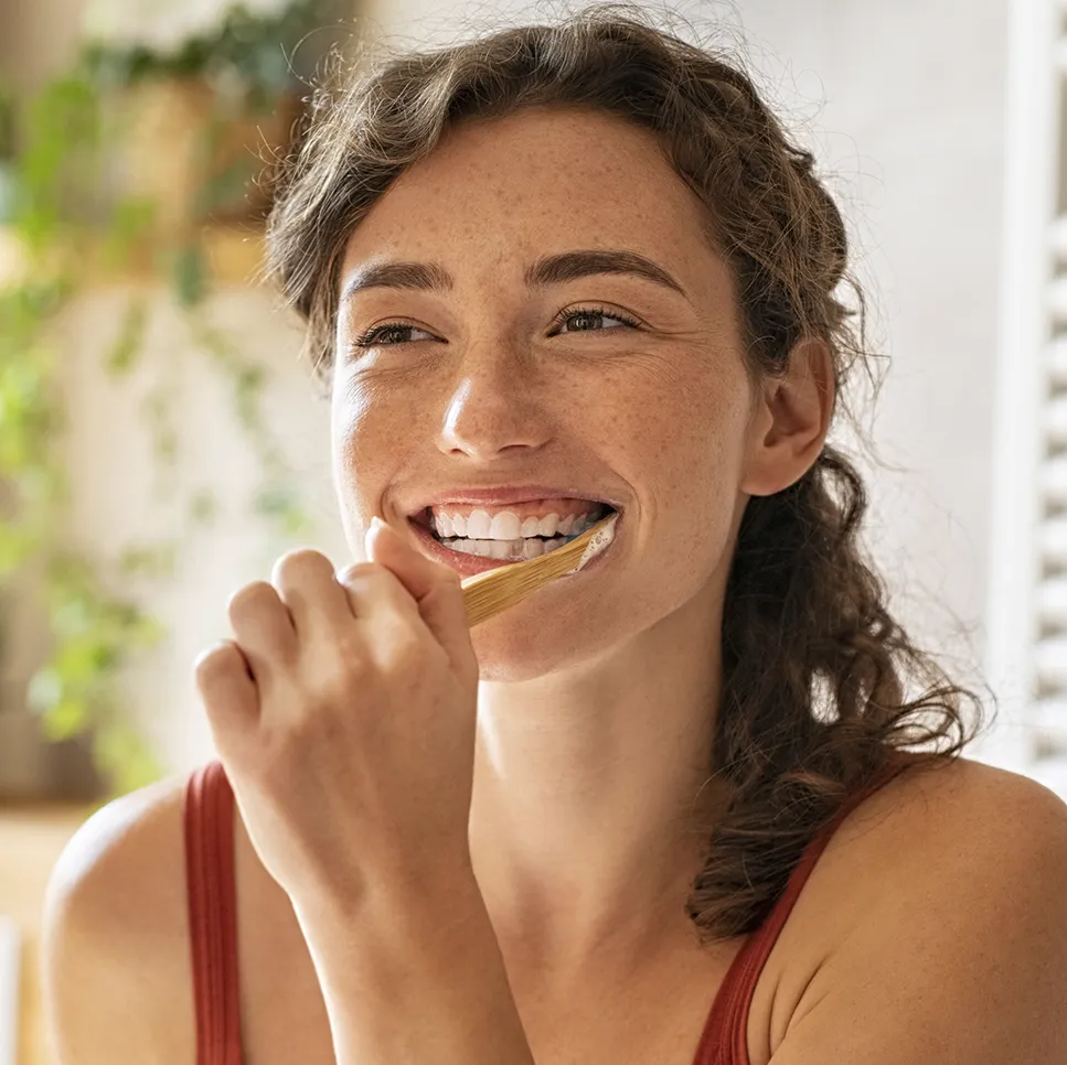 A happy woman brushing her teeth