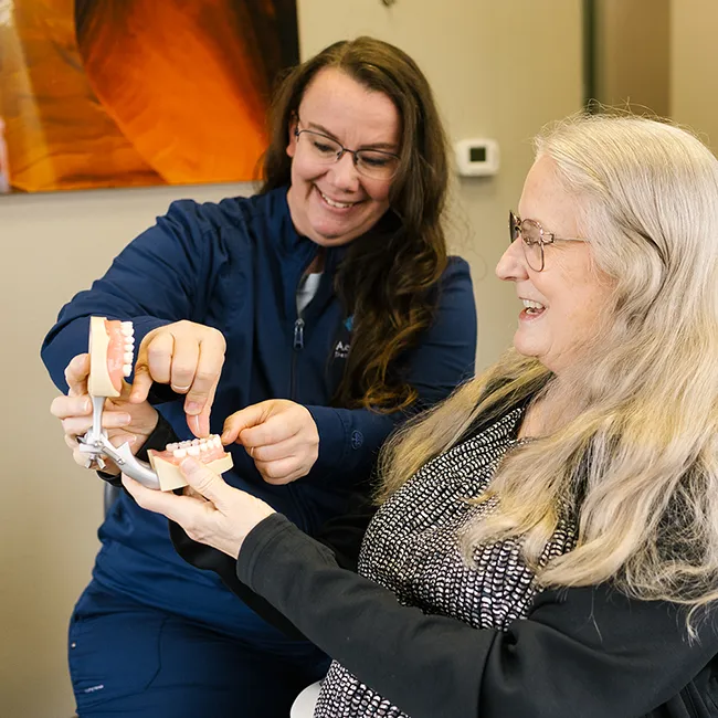 Dental Hygienist Showing Dentures To A Patient