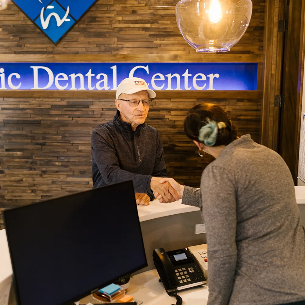 Full Mouth Dental Implants Patient Shaking Hands at Front Desk